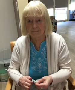 Elderly lady sitting in chair & knitting
