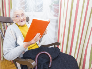 Hardi Aged Care elderly resident sitting in rocking chair reading a book.